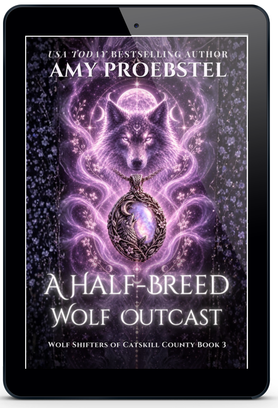 A tablet device centered on a light gray background, displaying the book cover for 'A Half-Breed Wolf Outcast' by Amy-Proebstel. The cover art features a purple wolf and magical pendant illustration on a dark background.