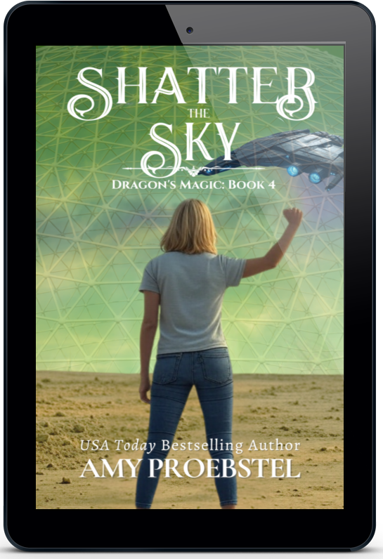 A black tablet device displaying the book cover for 'Shatter the Sky' by Amy Proebstel. The cover art features a woman seen from behind standing in a desert landscape, pointing toward a large geodesic dome under a green sky with a spaceship overhead.