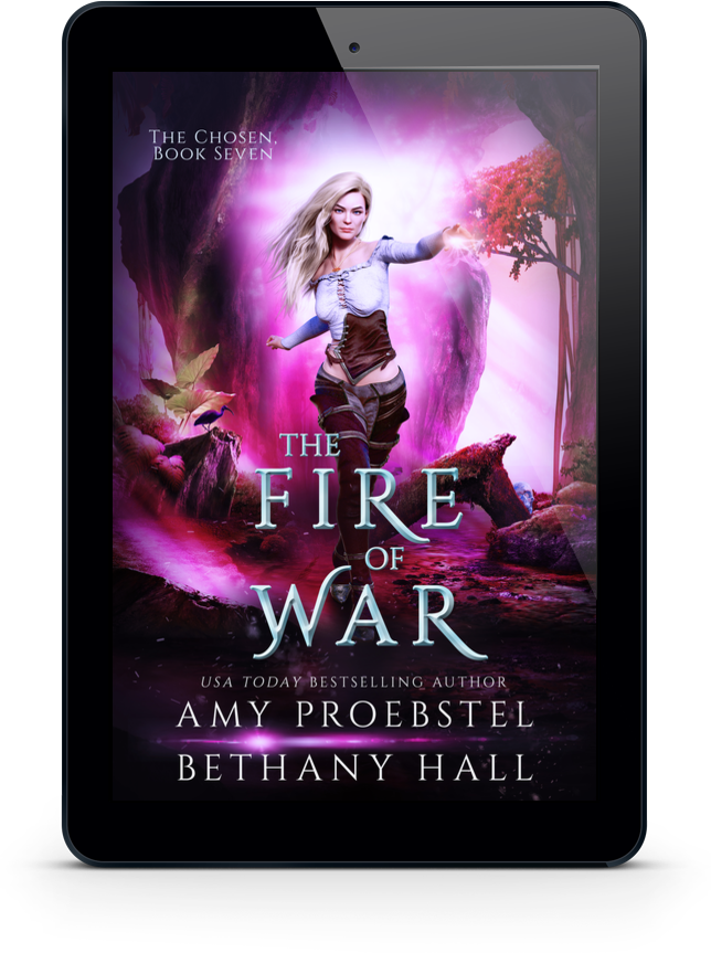 A black tablet device centered on a white background, displaying the book cover for 'The Fire of War' by Amy Proebstel and Bethany Hall. The cover art features a fantasy scene with a woman in a white and brown outfit against a glowing pink and purple landscape.