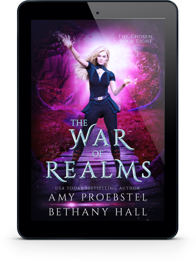 A black tablet device centered on a white background, displaying the book cover for 'The War of Realms' by Amy Proebstel Bethany Hall. The cover art shows a fantasy scene with a blonde woman in dark clothing against a glowing purple and pink magical forest backdrop.