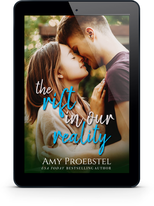 A black tablet device displaying a romance novel cover with a couple embracing closely. The cover text reads 'the rift in our reality' in white and blue script, with 'AMY PROEBSTEL USA TODAY BESTSELLING AUTHOR' at the bottom.